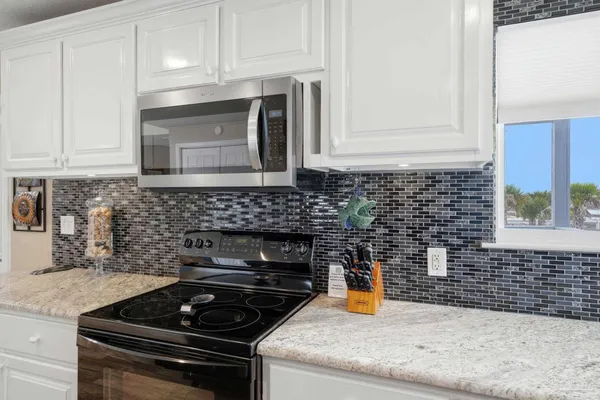 a kitchen with stainless steel appliances granite countertop white cabinets and a stove