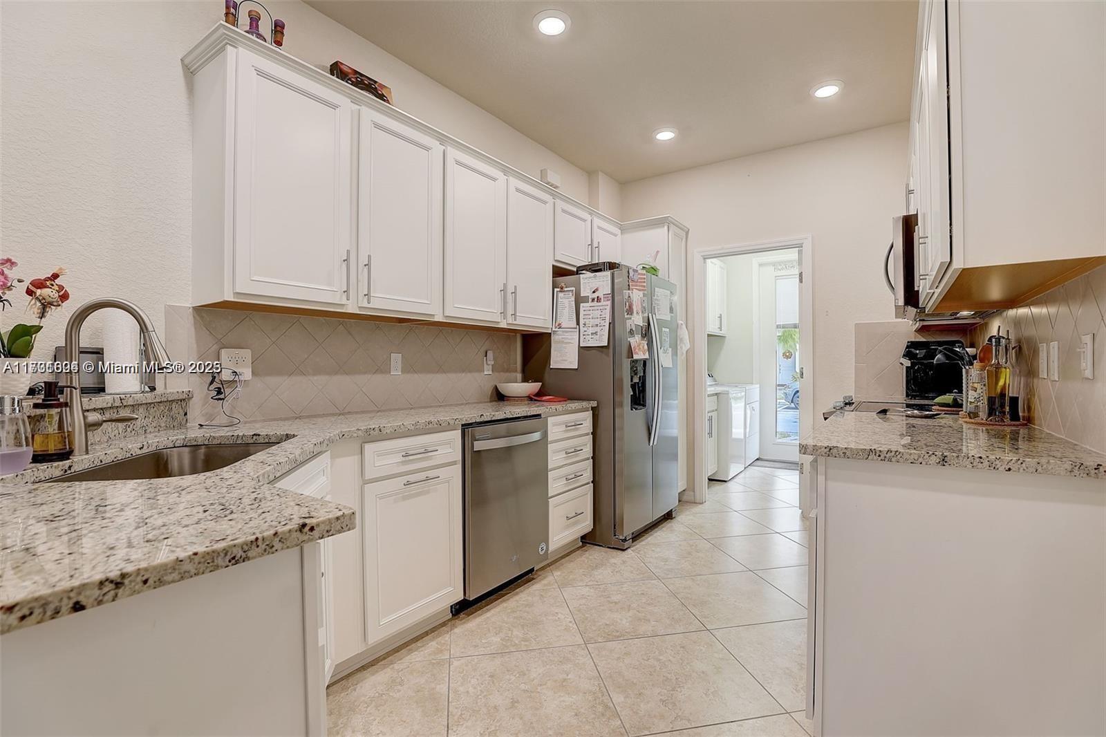 a kitchen with kitchen island granite countertop a sink stainless steel appliances and cabinets