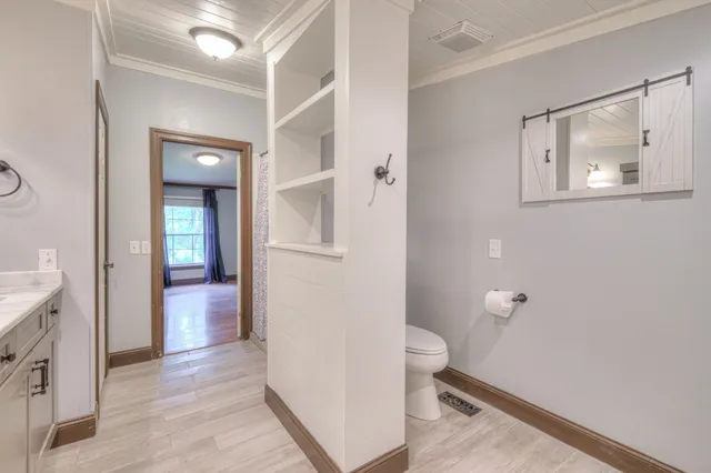 a view of a hallway with wooden floor and a bathroom