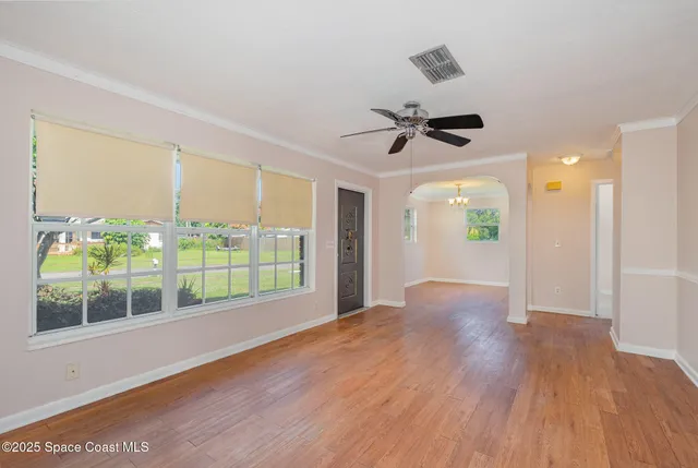 a view of an empty room with a window and wooden floor