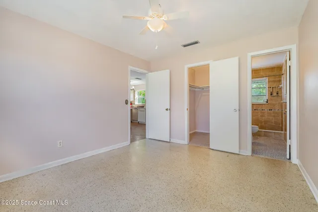 an empty room with closet and a chandelier fan