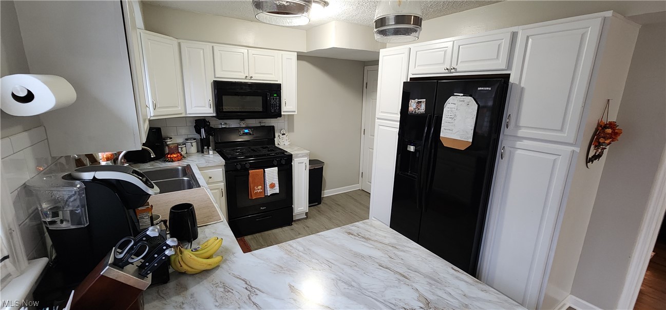 1293 Brainard Road Lyndhurst, OH 44124 - Photo 8 of 15 Kitchen featuring black appliances, sink, tasteful backsplash, and white cabinetry