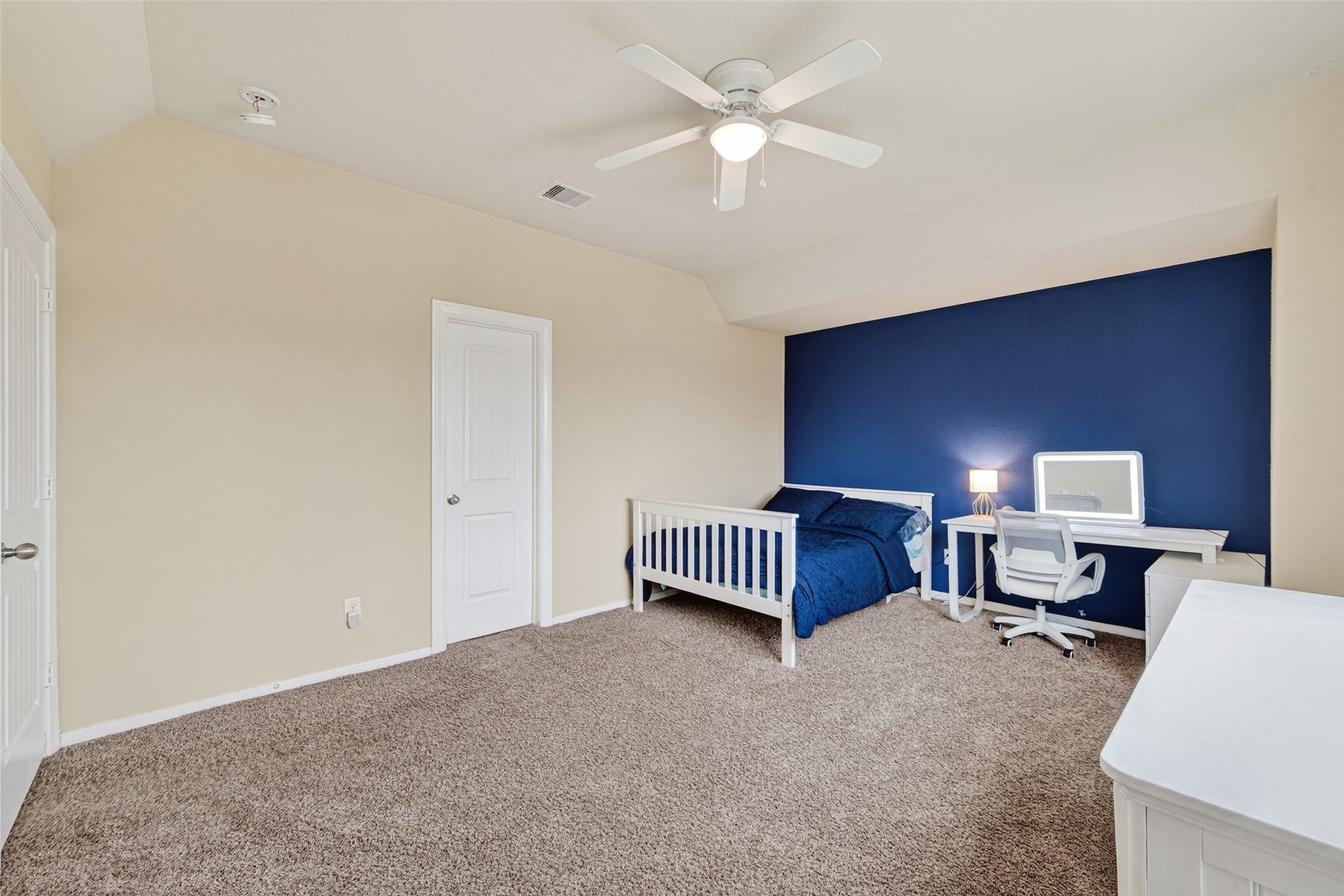 25611 Ellis Ridge Court Katy, TX 77494 - Photo 33 of 49 This spacious bedroom features a cozy carpet, a ceiling fan, and a contrasting blue accent wall. It includes a bed, desk, and chair, offering a comfortable and functional setup.
