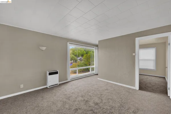 an empty room with floor to ceiling window and an outdoor view
