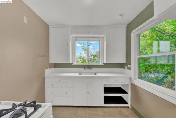 a view of kitchen with a sink wooden cabinets and a window