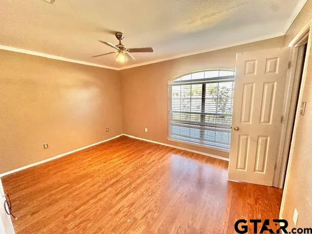 an empty room with wooden floor fan and windows