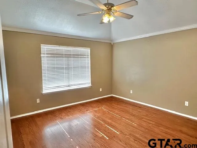 a view of an empty room with a window and wooden floor