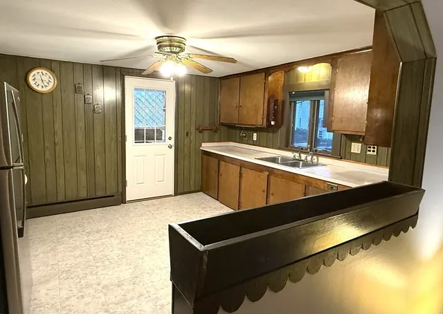 a view of a kitchen with kitchen island a sink stainless steel appliances wooden floor and a chandelier