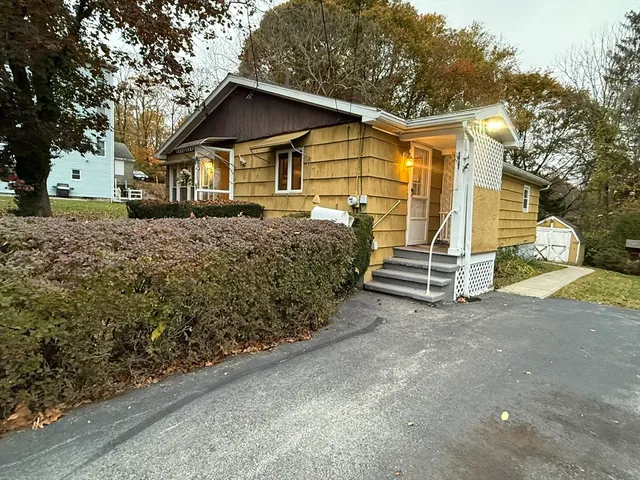 a view of a house with a yard and large tree