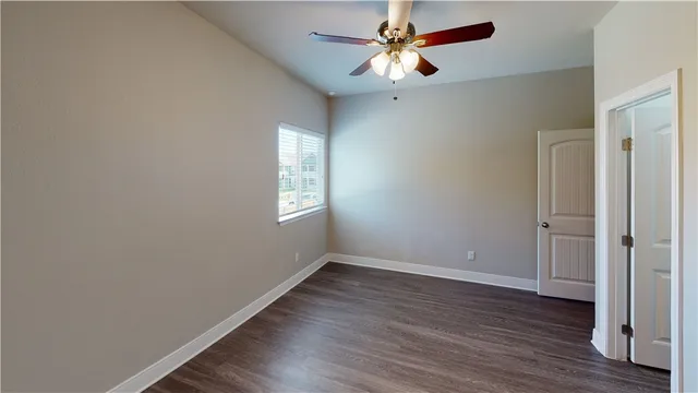 an empty room with wooden floor fan and windows