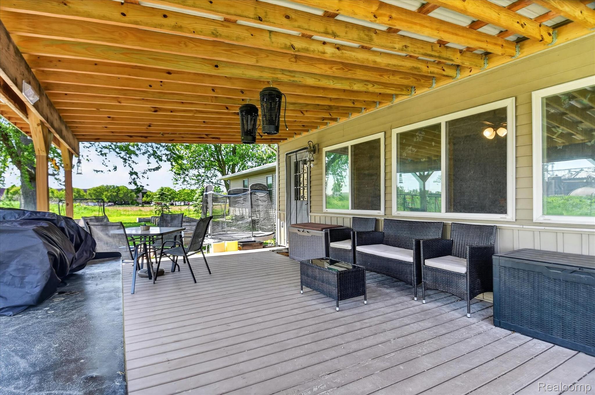 3949 West Burns Line Road Brown City, MI 48416 - Photo 62 of 70 Covered outdoor patio area featuring a slatted wood-finish ceiling, composite decking, and multiple large windows along the exterior wall