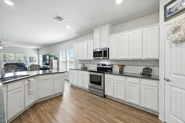 a kitchen with granite countertop white cabinets stainless steel appliances and a counter space