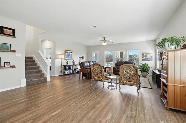 a living room with furniture a flat screen tv and wooden floor