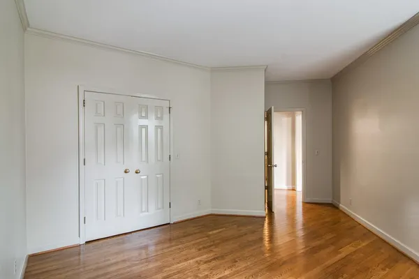 a view of an empty room with wooden floor and closet