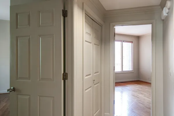 a view of an empty room with wooden floor and closet