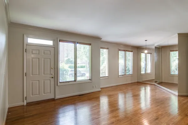 a view of an empty room with wooden floor and a window