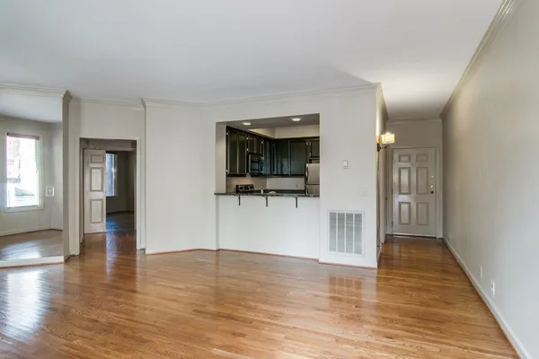 a view of a hallway with wooden floor and a living room