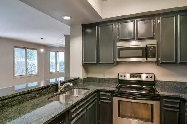 a kitchen with granite countertop a sink stainless steel appliances and cabinets