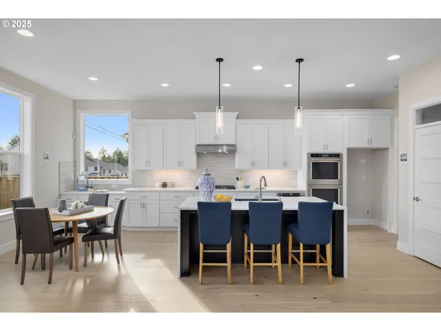 a kitchen with stainless steel appliances kitchen island granite countertop a dining table chairs and sink