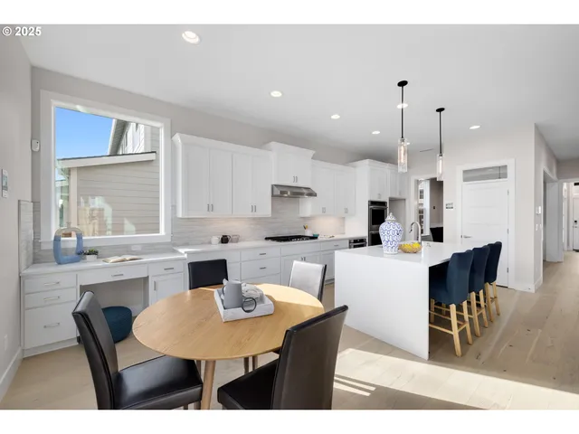 a dining room with stainless steel appliances kitchen island granite countertop a dining table chairs and a refrigerator