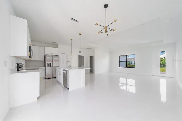 a view of a kitchen with kitchen island a counter top space stainless steel appliances and a large window