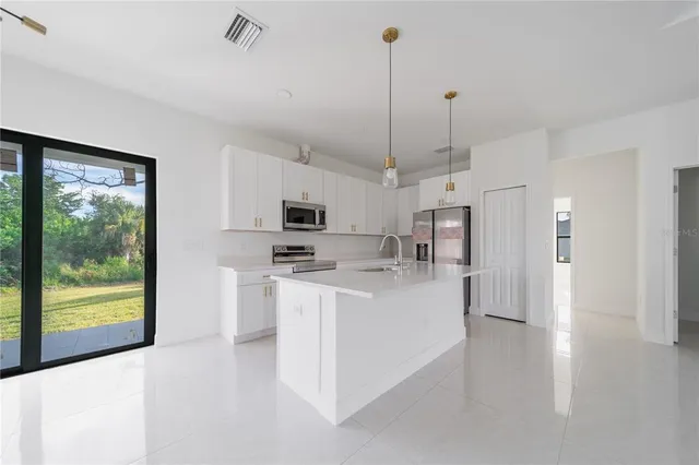 a kitchen with stainless steel appliances a sink a stove a refrigerator a center island and cabinets