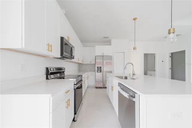 a kitchen with stainless steel appliances granite countertop a sink a refrigerator and a stove