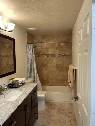 a bathroom with a granite countertop sink a toilet and shower