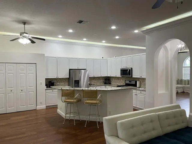 a living room with stainless steel appliances kitchen island granite countertop couches a fireplace a flat screen tv and kitchen view