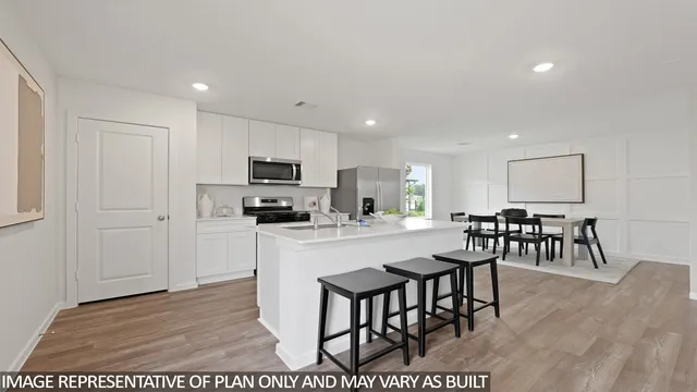 a kitchen with stainless steel appliances granite countertop a stove a sink a microwave a dining table and chairs with wooden floor