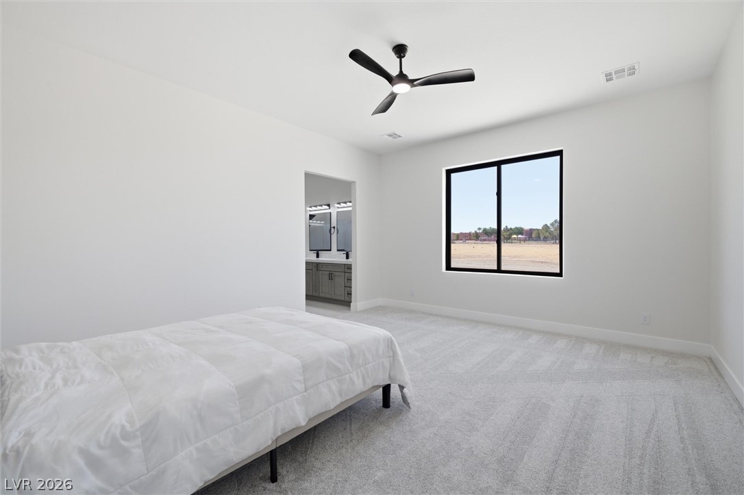 5910 East Kellogg Road Pahrump, NV 89061 - Photo 31 of 58 A well-lit bedroom features plush carpeting, a modern ceiling fan, and a view of the outdoors.
