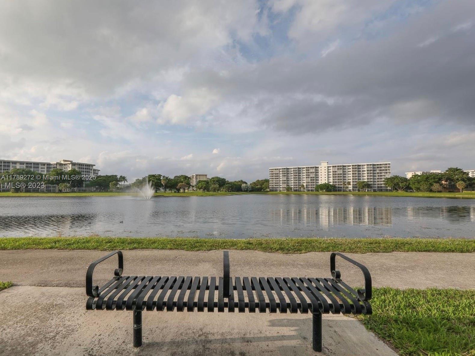 2751 North Palm Aire Drive, Unit 310 Pompano Beach, FL 33069 - Photo 66 of 70 a view of a lake with a bench and lake view