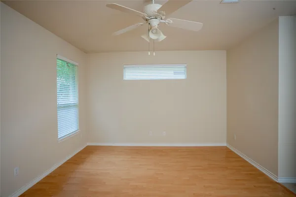 an empty room with chandelier fan and windows