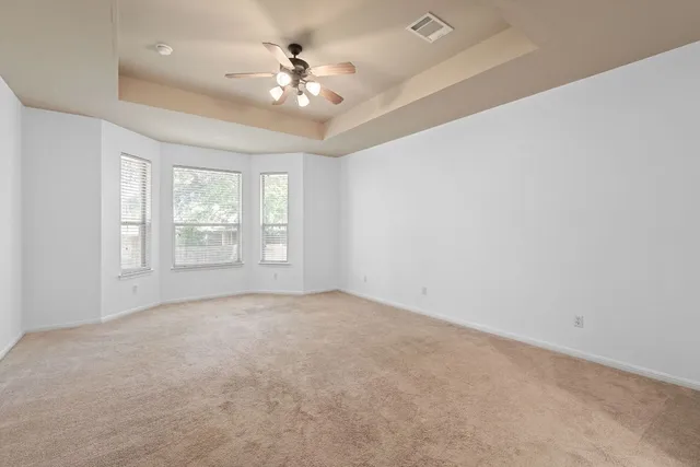 an empty room with windows and chandelier fan