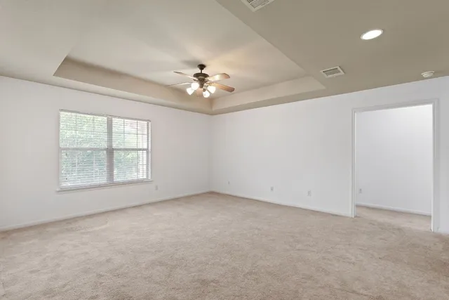 an empty room with a chandelier fan and windows