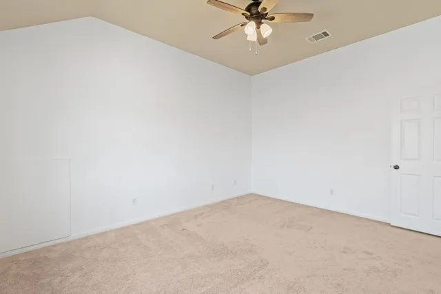 an empty room with a chandelier fan and closet