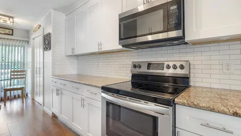 a kitchen with granite countertop cabinets stainless steel appliances and wooden floor