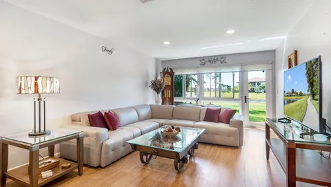 a living room with furniture flat screen tv and a large window