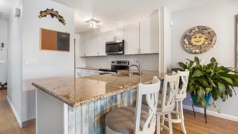 a kitchen with stainless steel appliances granite countertop a stove top oven a sink a dining table and chairs