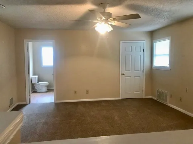 an empty room with windows and fan