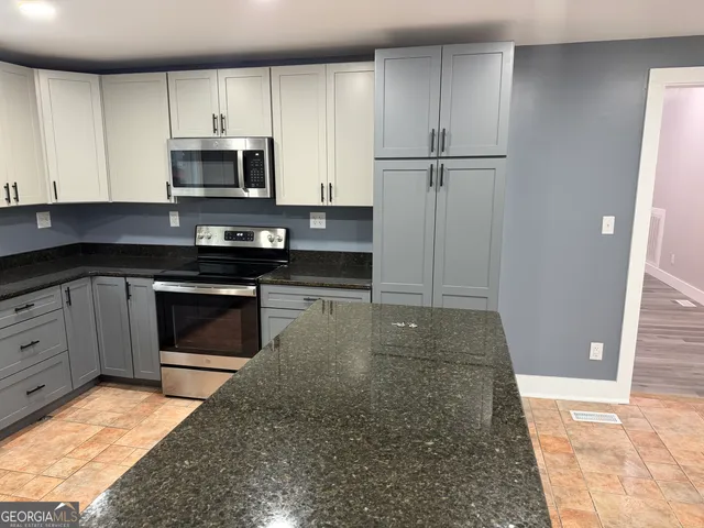 a kitchen with stainless steel appliances granite countertop a stove a microwave and a sink