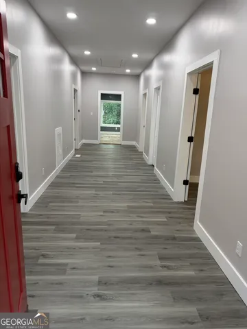 a view of an empty room with wooden floor and a bathroom