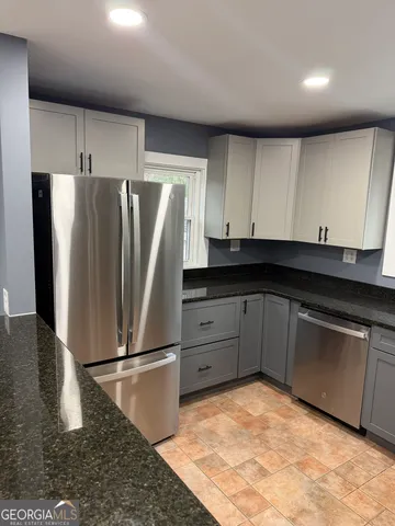a kitchen with granite countertop a refrigerator and a sink