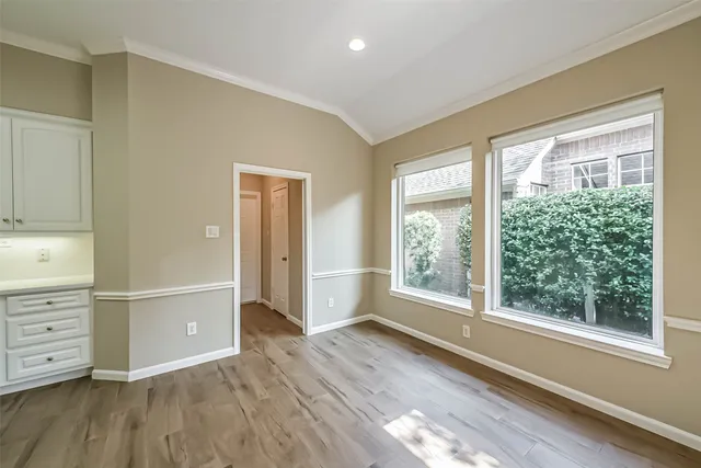 a view of an empty room with a window and wooden floor