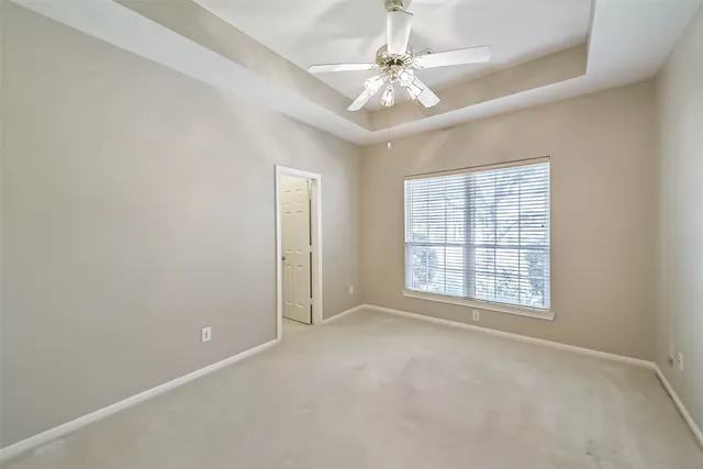 an empty room with chandelier fan and windows