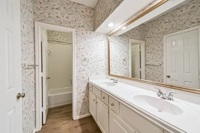 a spacious bathroom with a double vanity sink a mirror and a shower