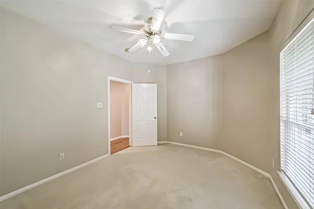 an empty room with chandelier fan and windows