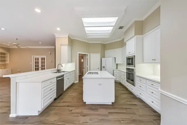 a large white kitchen with wooden floors and stainless steel appliances