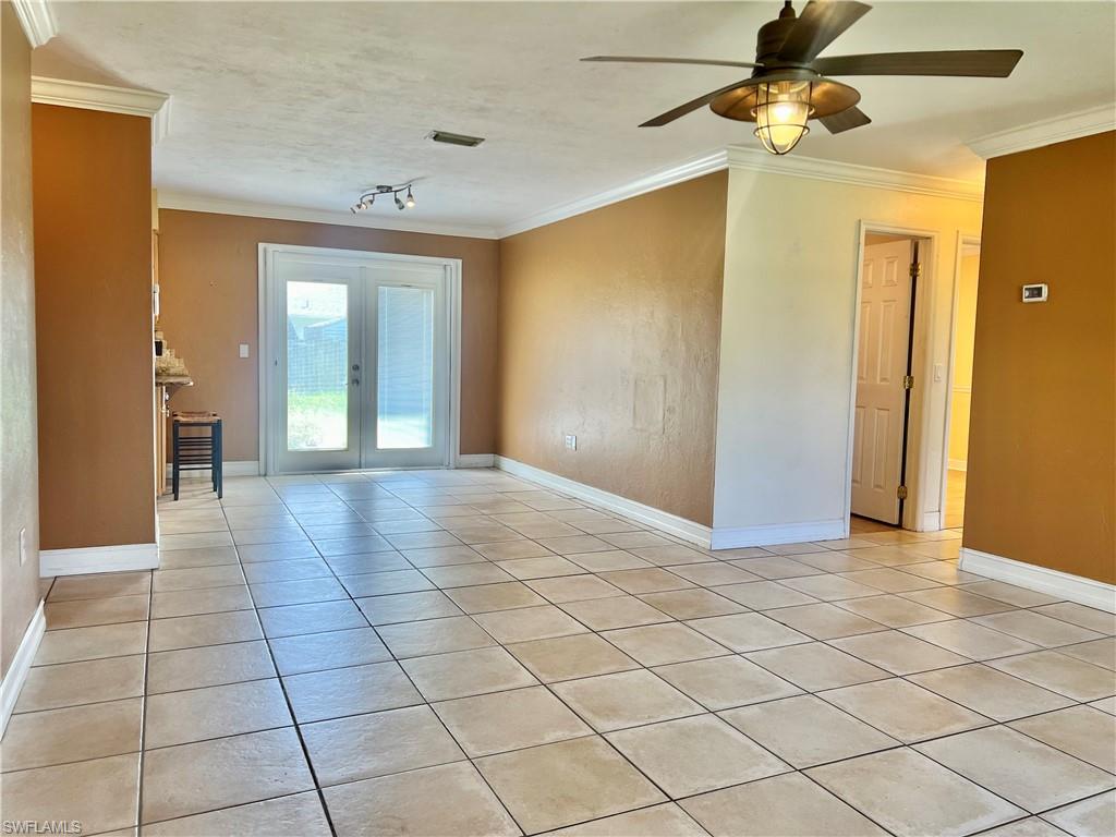 18581 Tampa Road Fort Myers, FL 33967 - Photo 11 of 25 Empty room with ceiling fan, french doors, light tile patterned floors, and ornamental molding