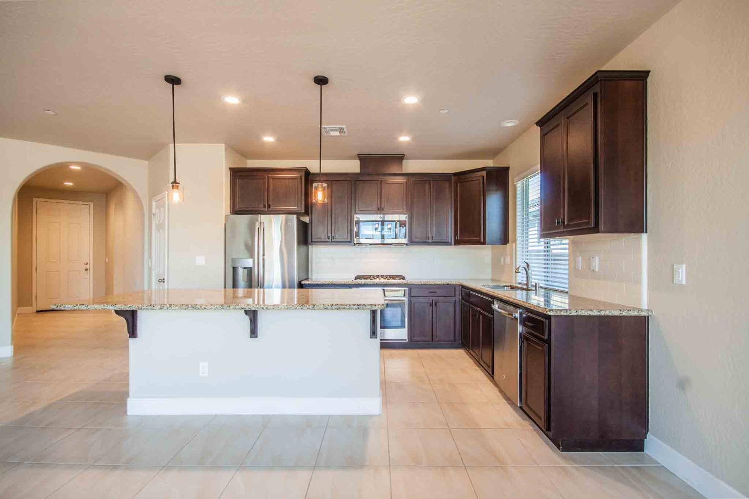 3439 Brimhall Lane Clovis, CA 93619 - Photo 11 of 43 a large kitchen with stainless steel appliances kitchen island a large counter top and a view of living room